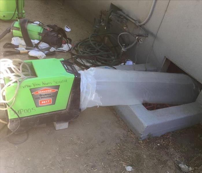 Dehumidifier set up outside crawlspace, with ducting attached.