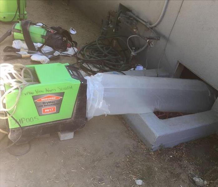 Dehumidifier set up outside crawlspace, with ducting attached. 