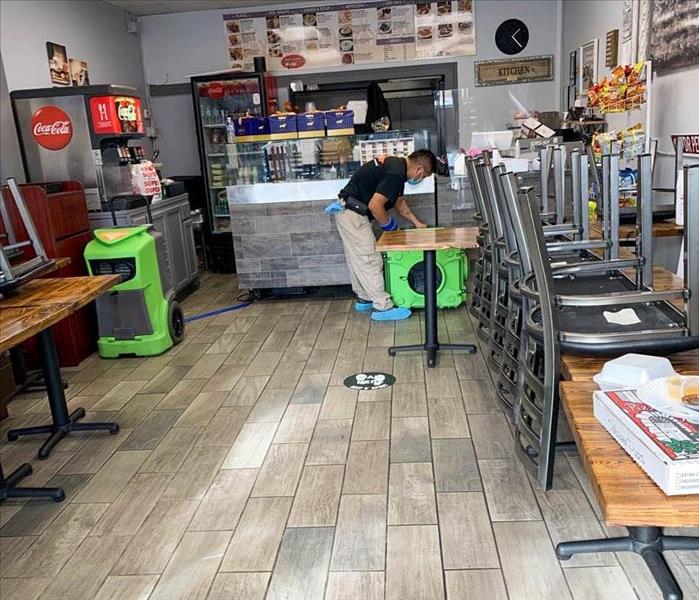 Lobby of restaurant water damaged and employee cleaning up