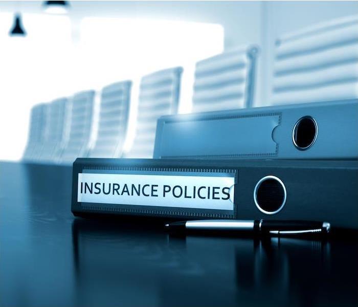 insurance policies binders and pen sitting on black table in large conference room