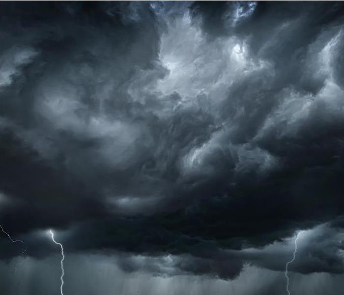 a dark cloudy sky with lighting strikes off in the distance