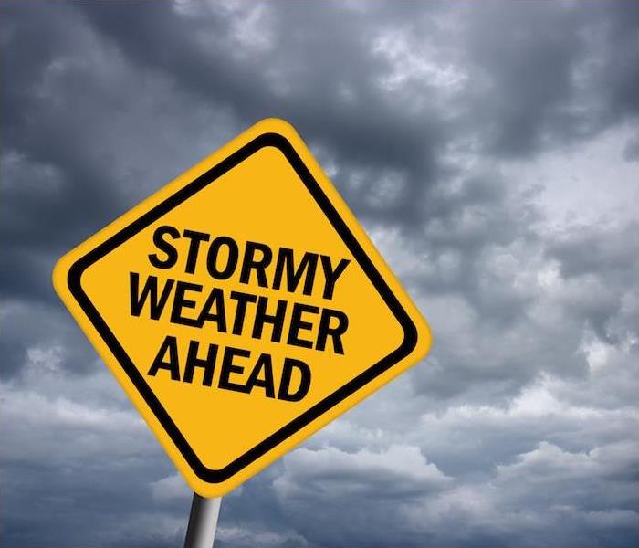 large yellow storm warning sign in front of dark forming clouds