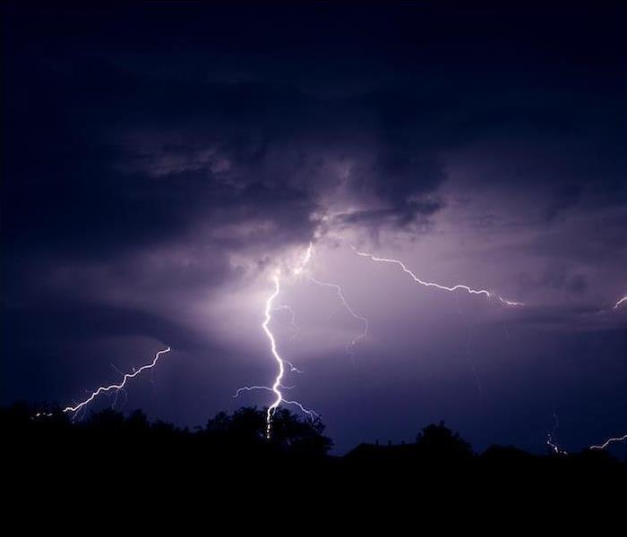 multiple lightning strikes off in distance of dark purple night sky