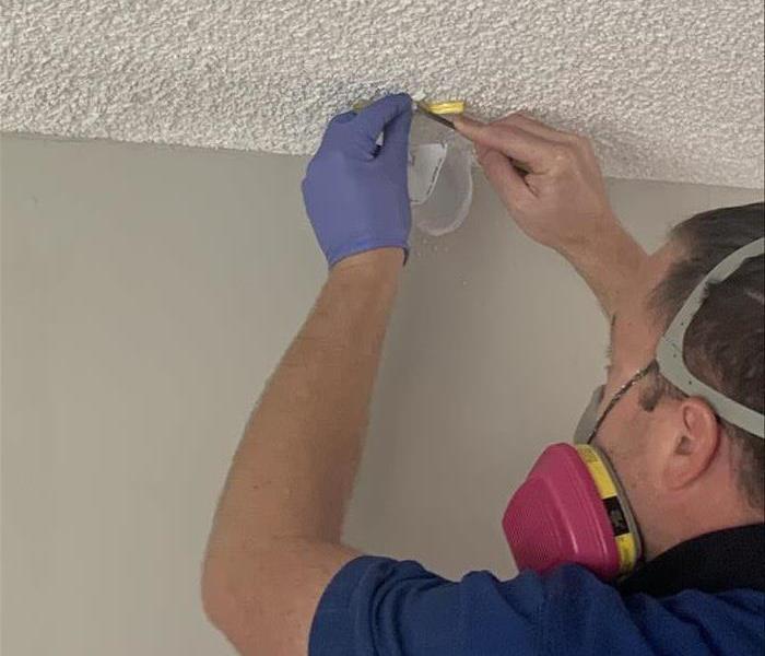 Environmental Hygienist Technician pulling sample of ceiling texture for asbestos testing